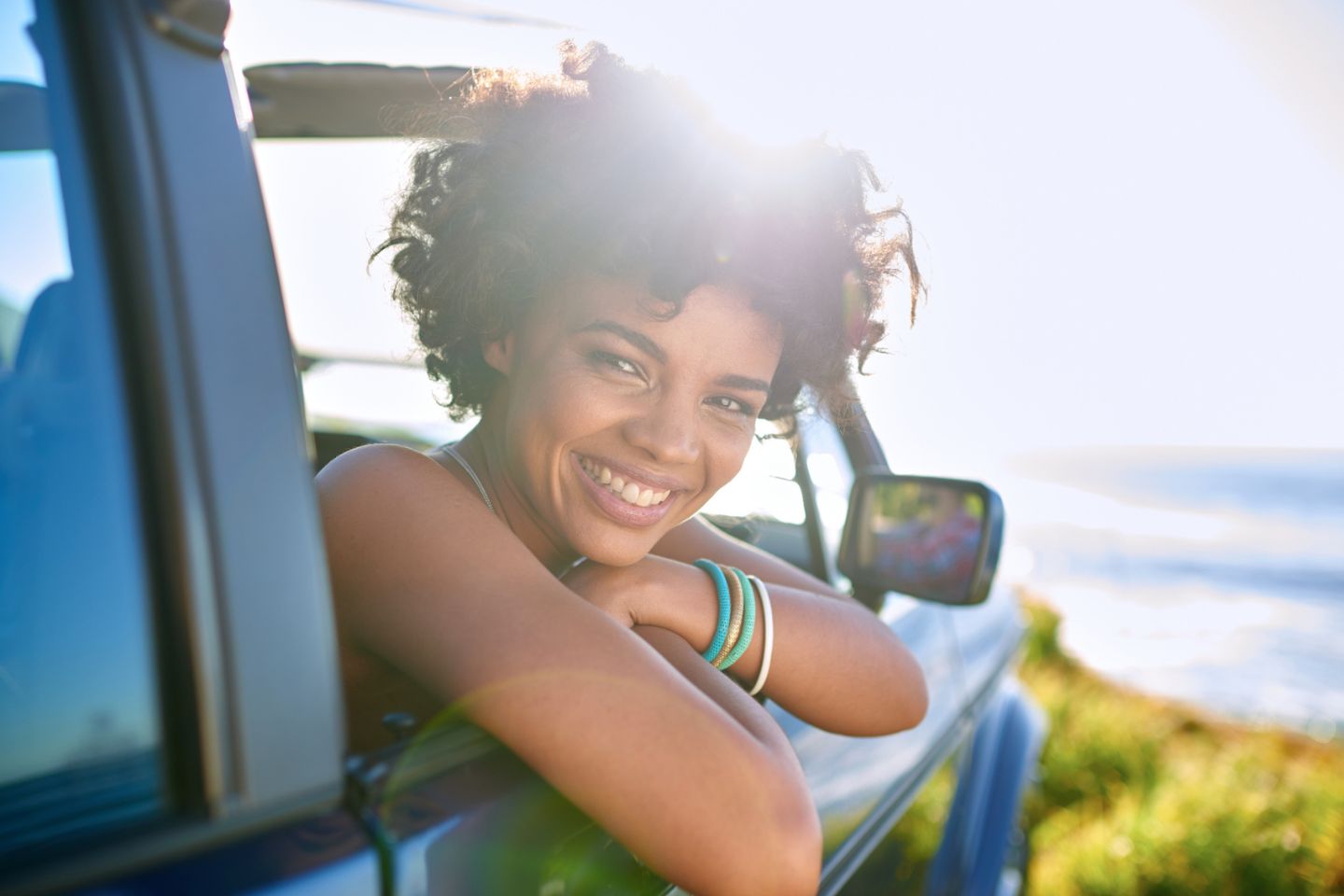 woman posing for picture leaning out of car while smiling