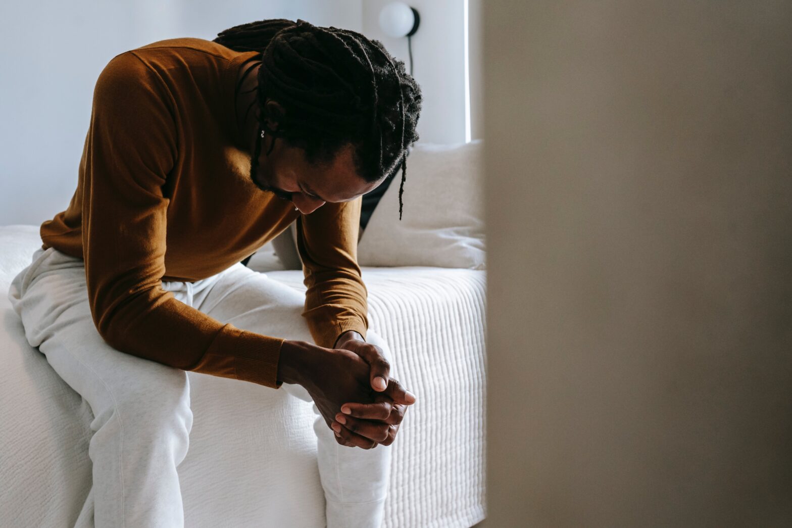 man sitting one edge of the bed comtemplating