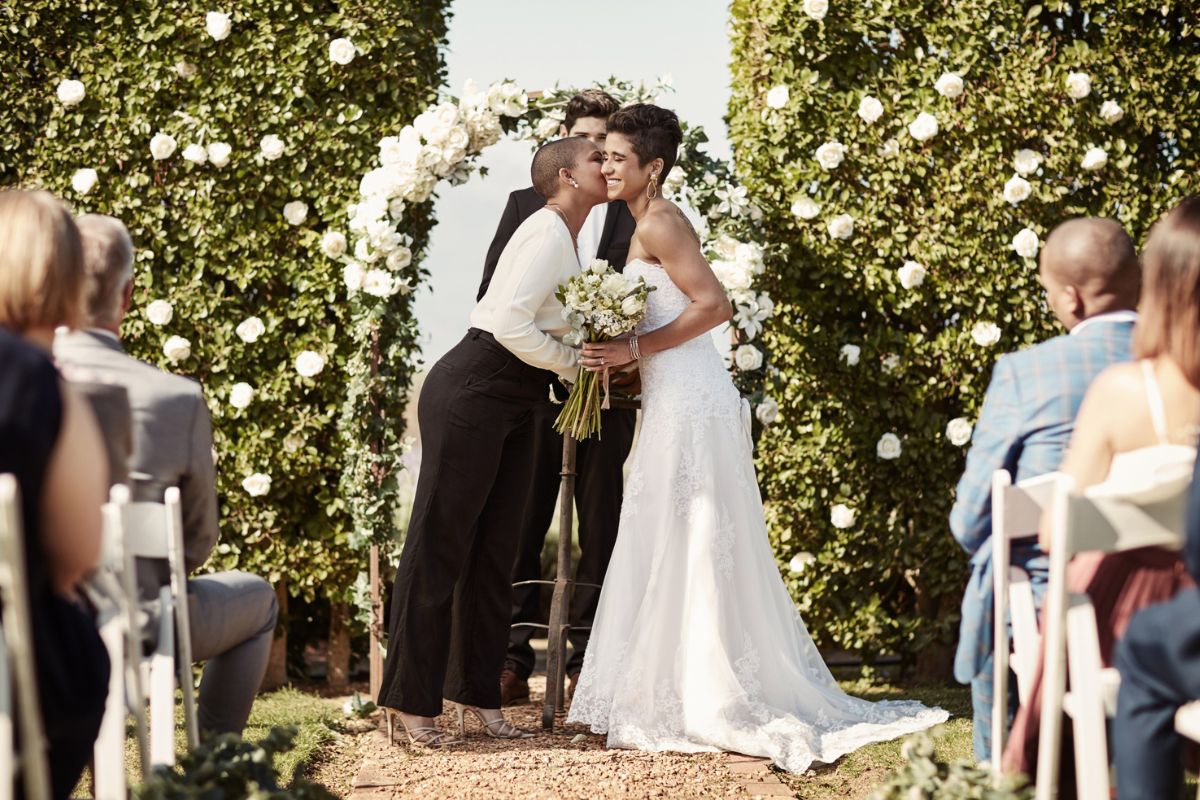 woman kissing her bride at the altar during their wedding ceremony