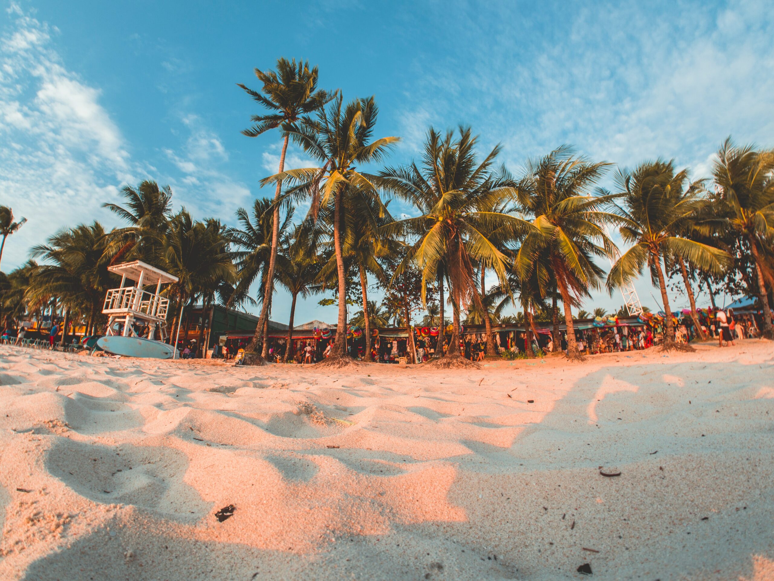 These are the best places to travel to in July. 
Pictured: a beach with white sands and lush green palm trees