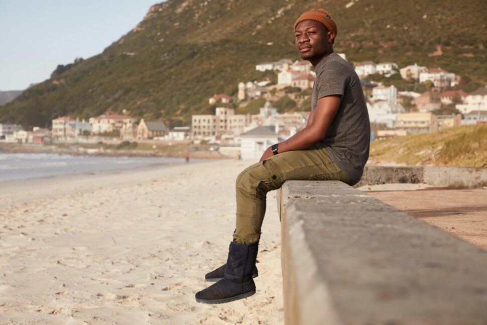 Pensive black man sitting on cement railing
