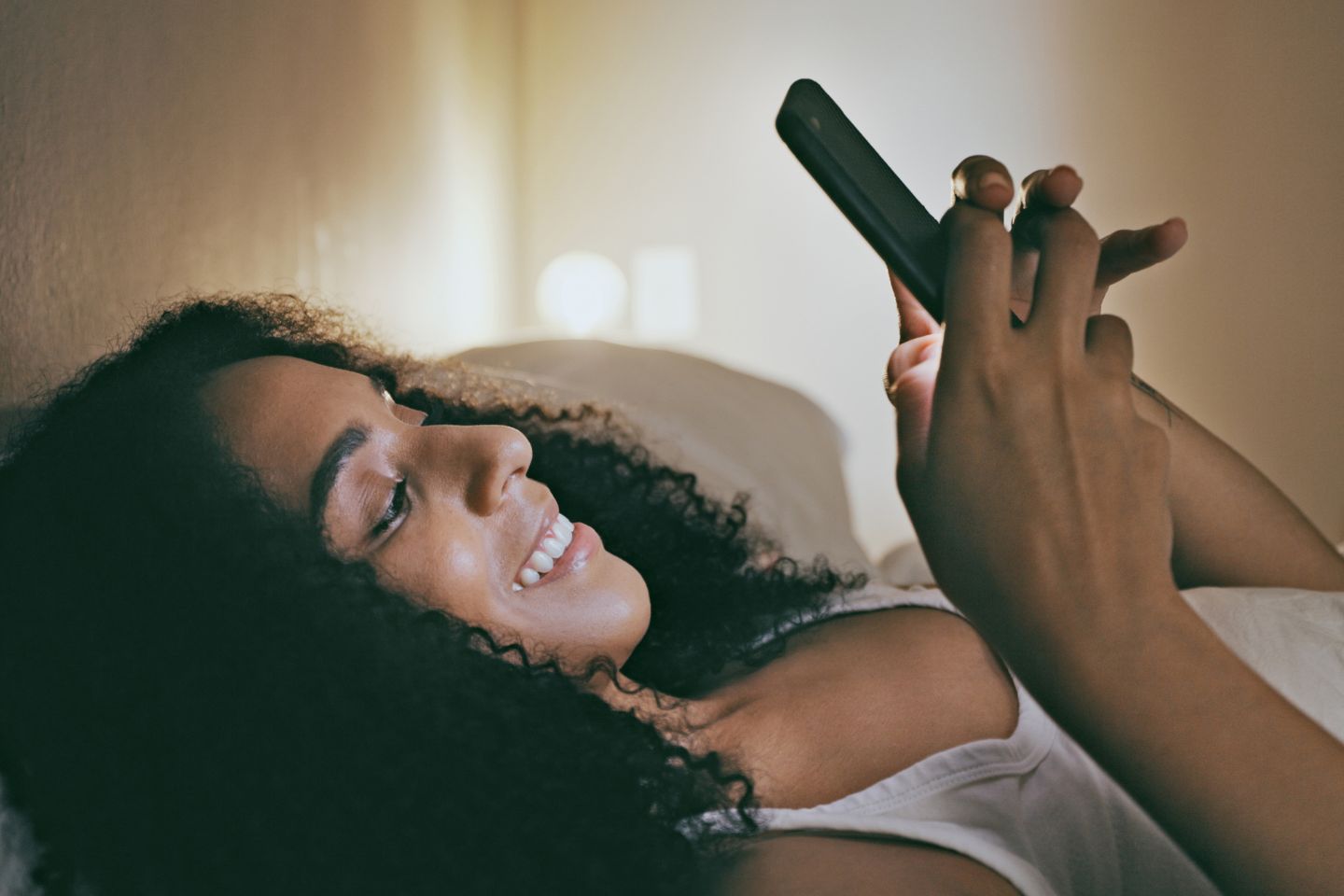 woman laying in the bed on the phone at night