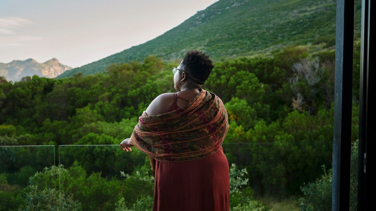 woman standing on balcony overlooking beautiful valley and mountains