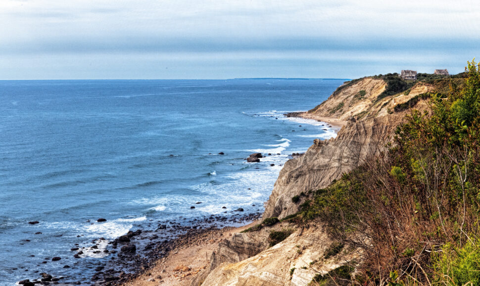 Dramatic colorful seaside view of the sandy bluffs along the coast of Block Island.  Summer day with small waves breaking along beach.