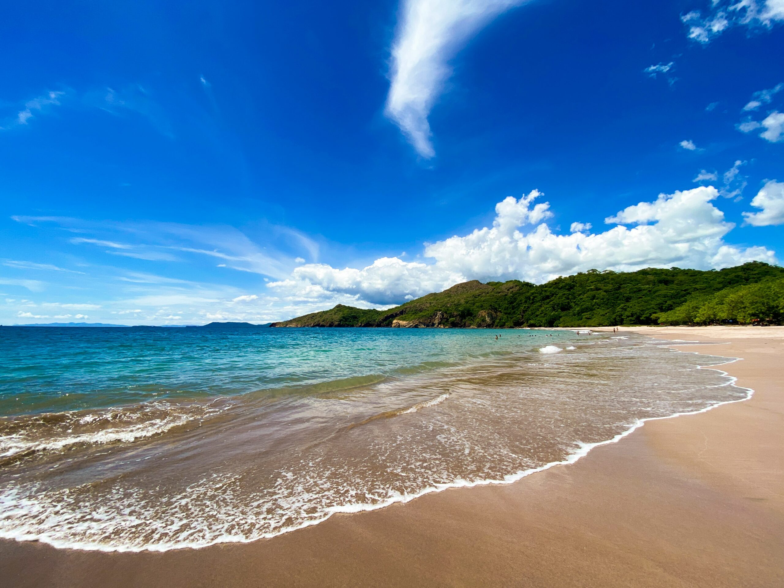 These are the safest countries in Central America that travelers should be sure to visit. 
Pictured: a beach with turquoise waters and lush green trees on a bright blue day