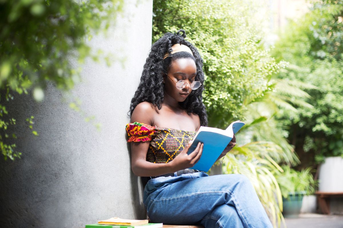 young woman reading a book in a lush garden