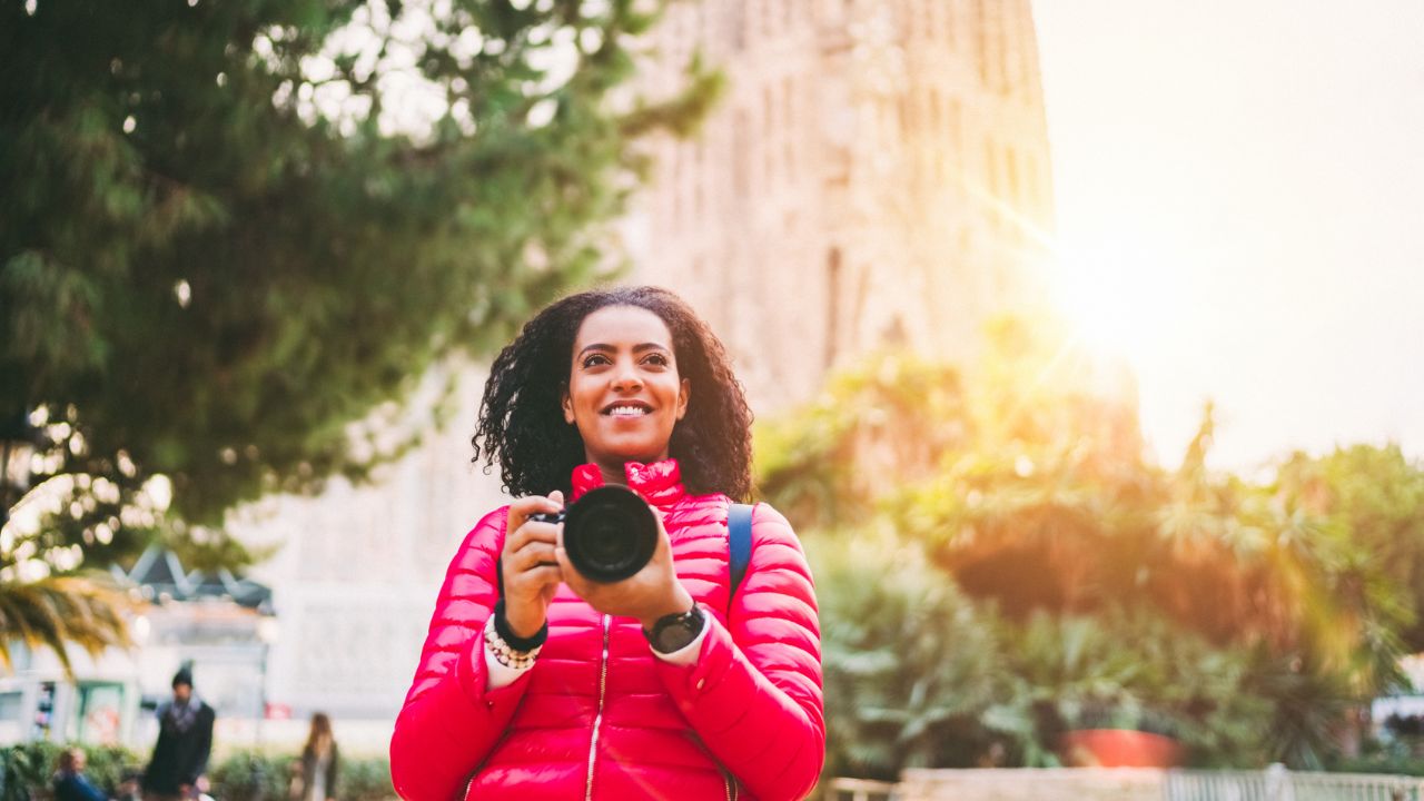 woman smiling with camera in hand while exploring Barcelona, Spain