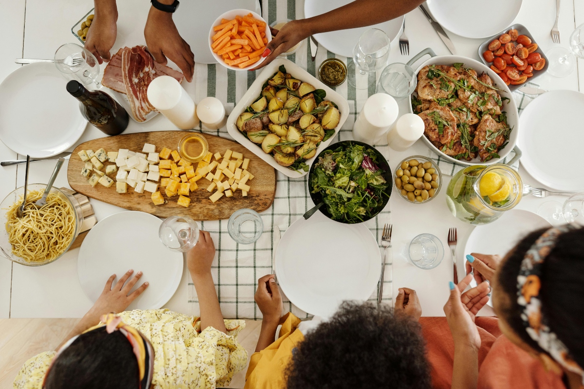 group of people sitting around a table with family-style dishes