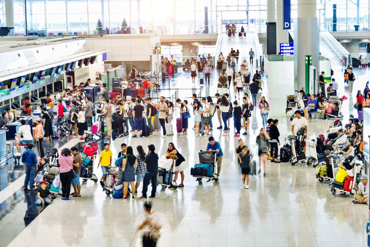 crowd of people walking through airport check-in area