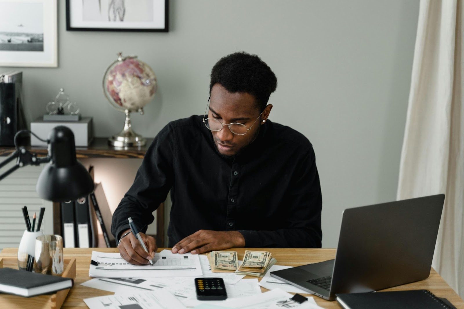 Travelers on a budget will appreciate Montana in September. 
pictured: a Black man budgeting in front of a world map