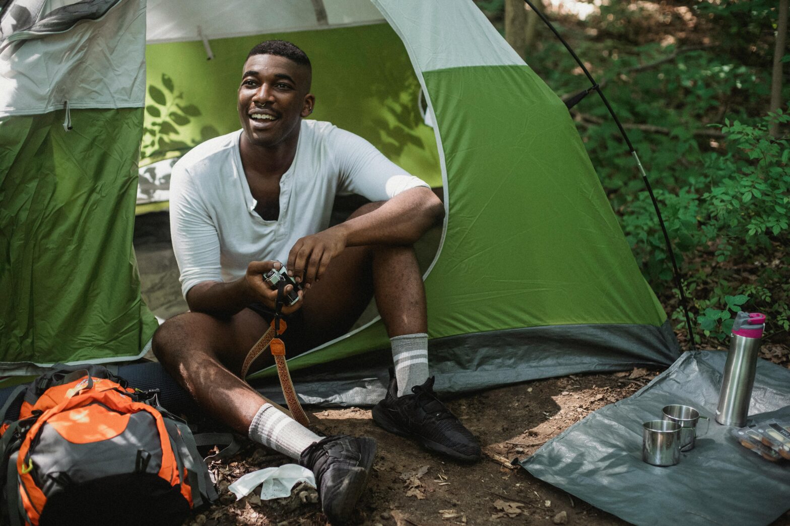 Black man relaxing in a tent in the forest, camping.