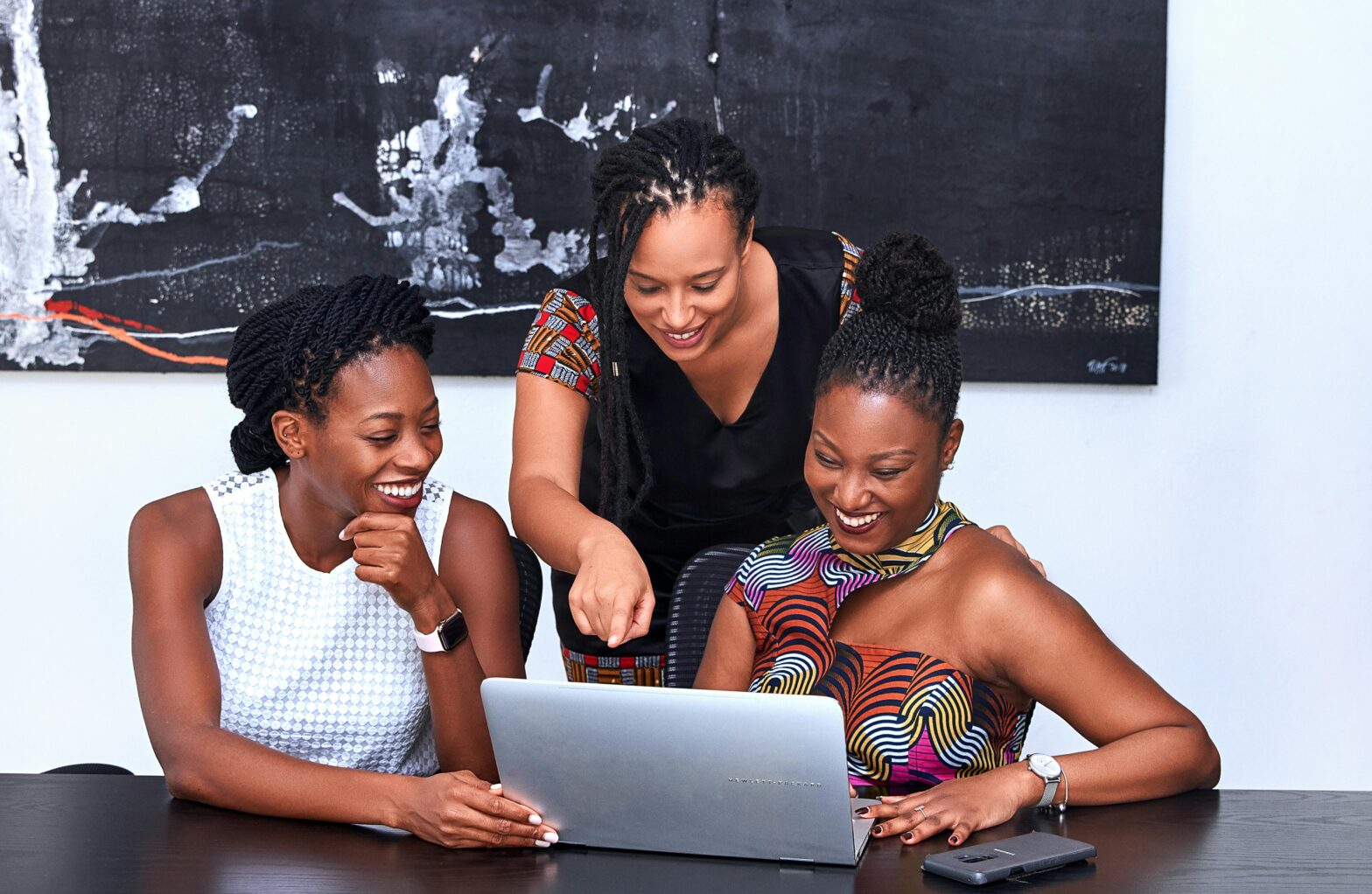 Three Black women looking at a computer screen.