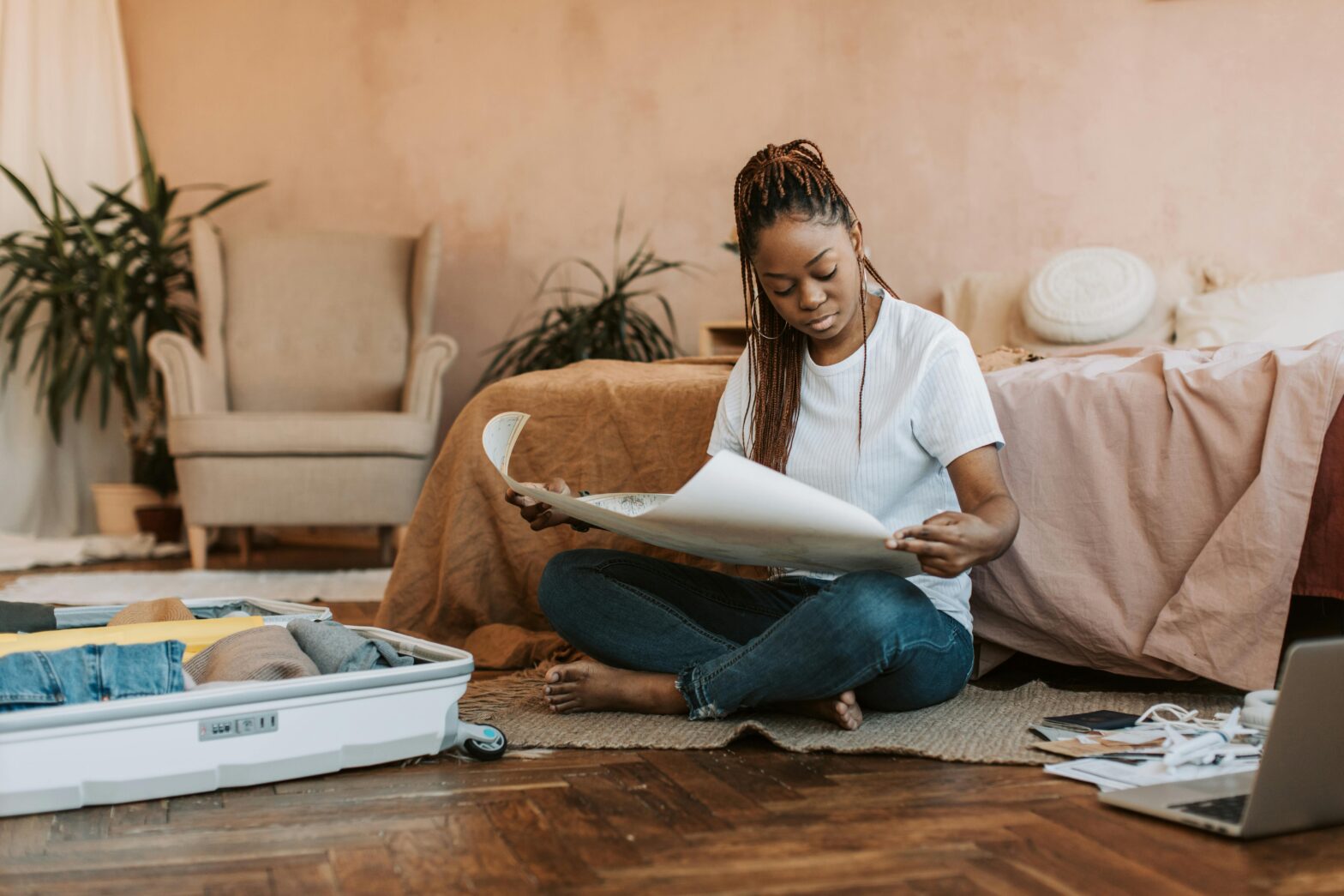 This recent study reports concerning numbers of solo women travelers feeling unsafe. pictured: a Black woman packing and looking at a world map