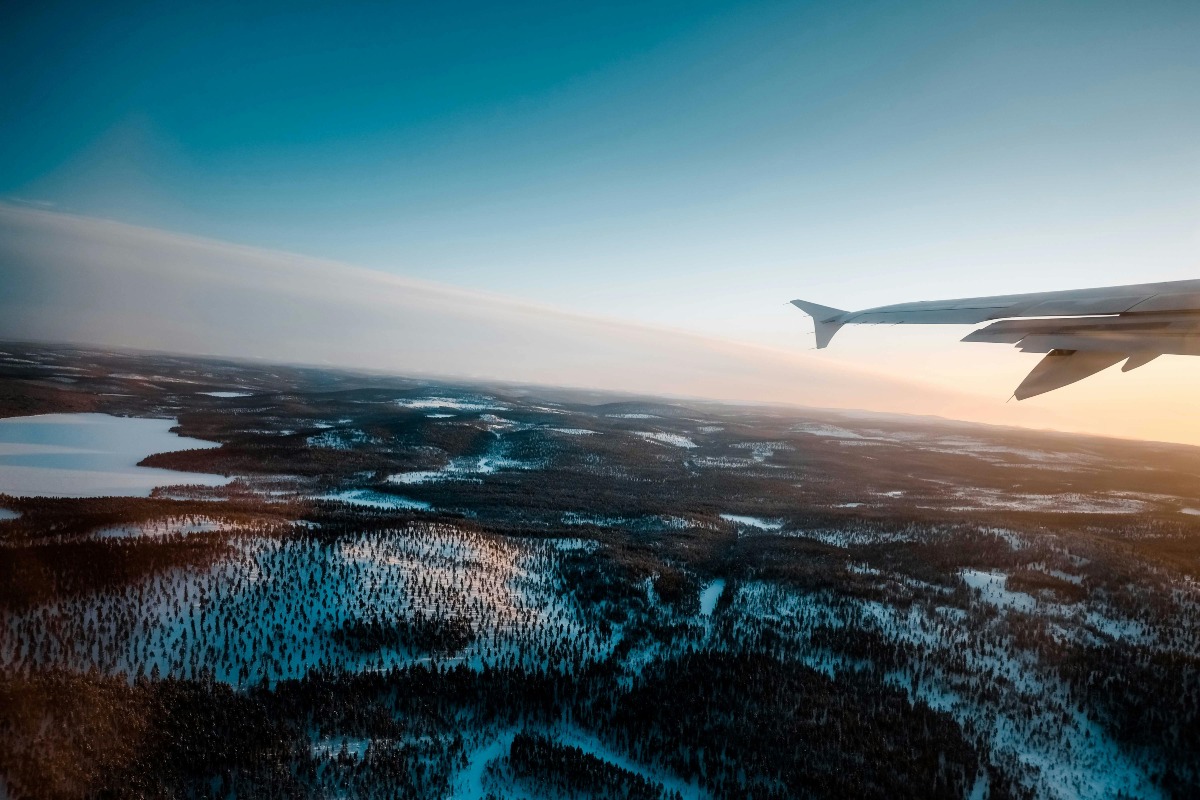 Aircraft flying over snowy forest in morning