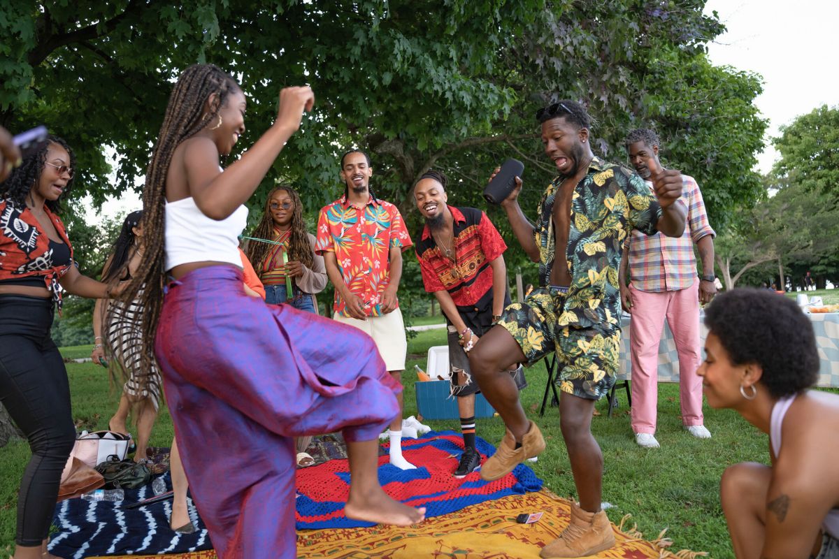 group of family and friends at park celebrating Juneteenth, laughing and dancing