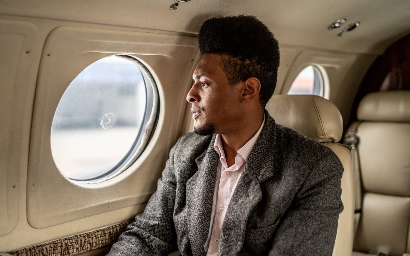 Black man contemplating on an airplane.