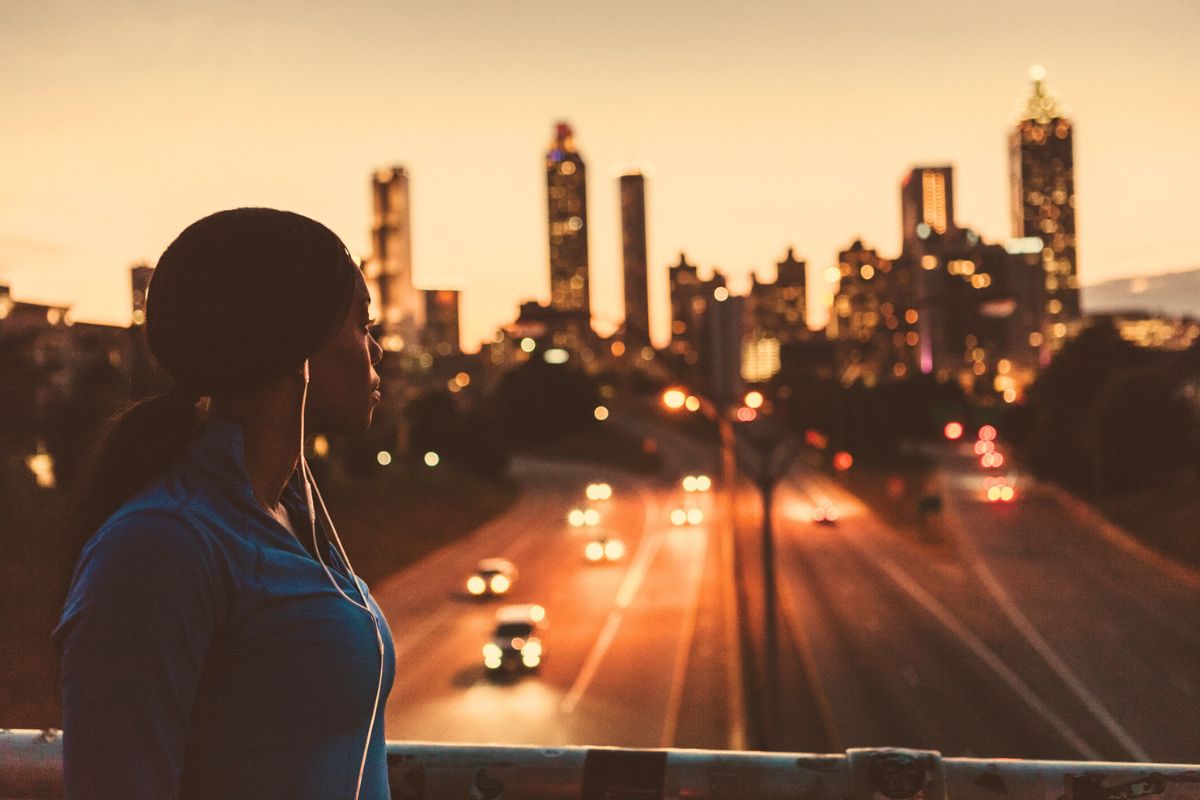 woman looking at Atlanta skyline during sunset from Jackson Street bridge