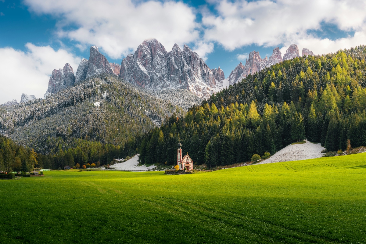 Green grass field near mountain under blue sky during daytime.