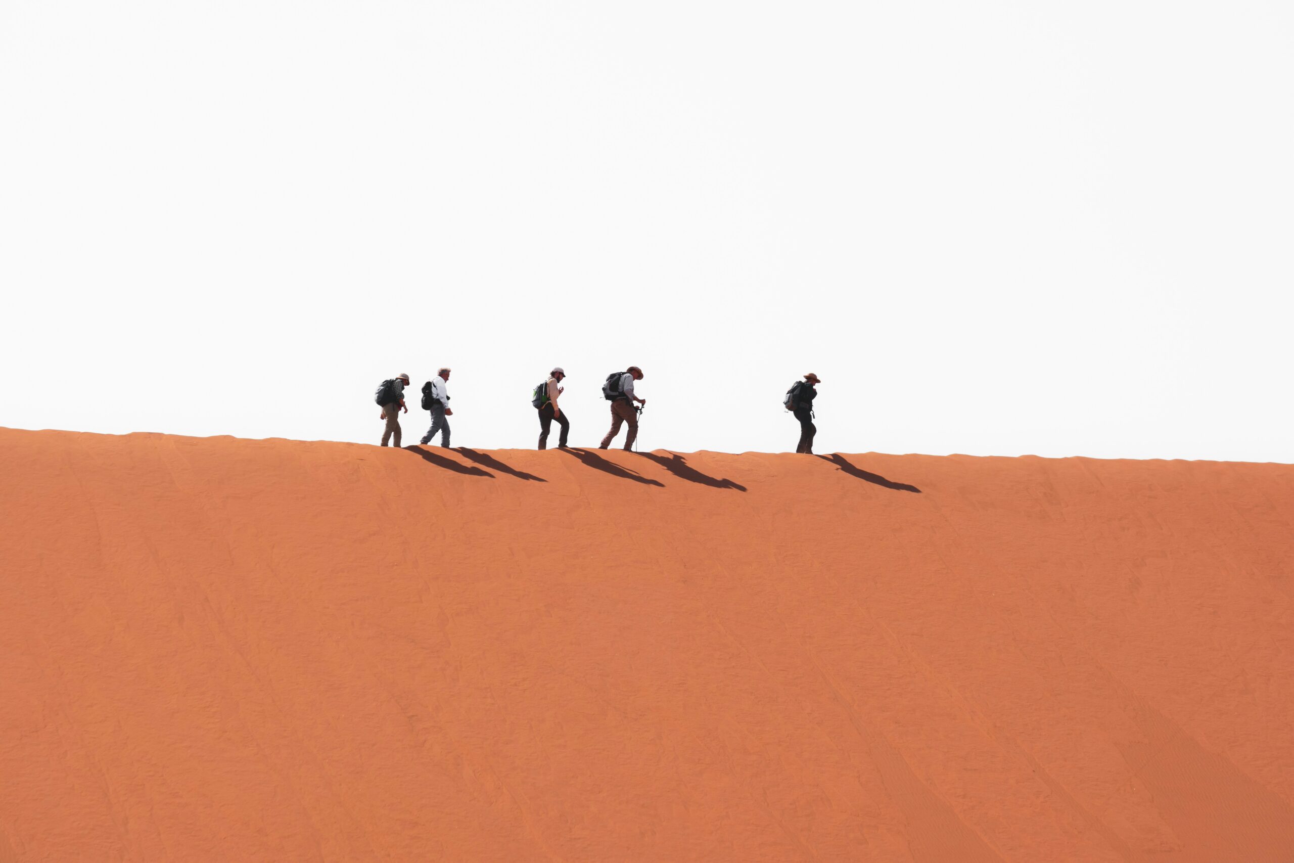 There are plenty of outdoor activities for travelers visiting Namibia in fall. 
Pictured: people walking through the Namibia dunes