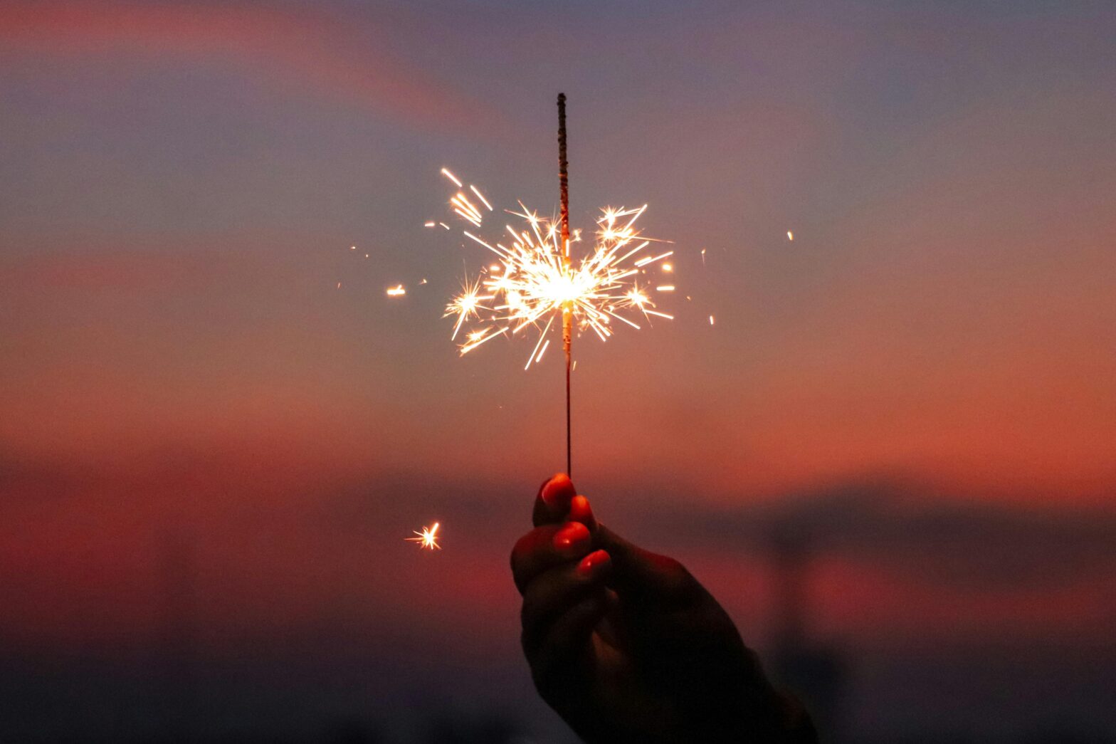 person holding a sparkler during beautiful sunset