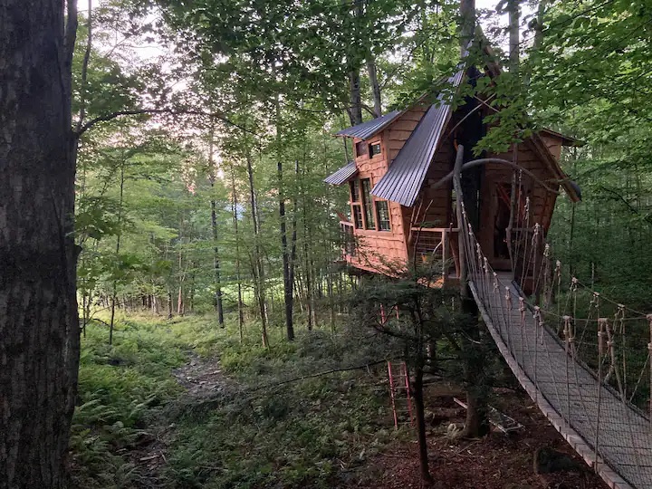 This treehouse is on a farm and is a great choice for travelers looking for off the grid Airbnbs. 
Pictured: treehouse in the woods