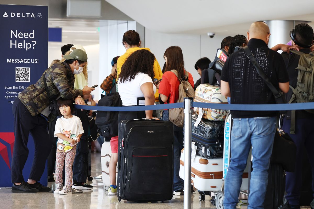 travelers waiting in check-in line at airport amid tech outages and air travel cancellations