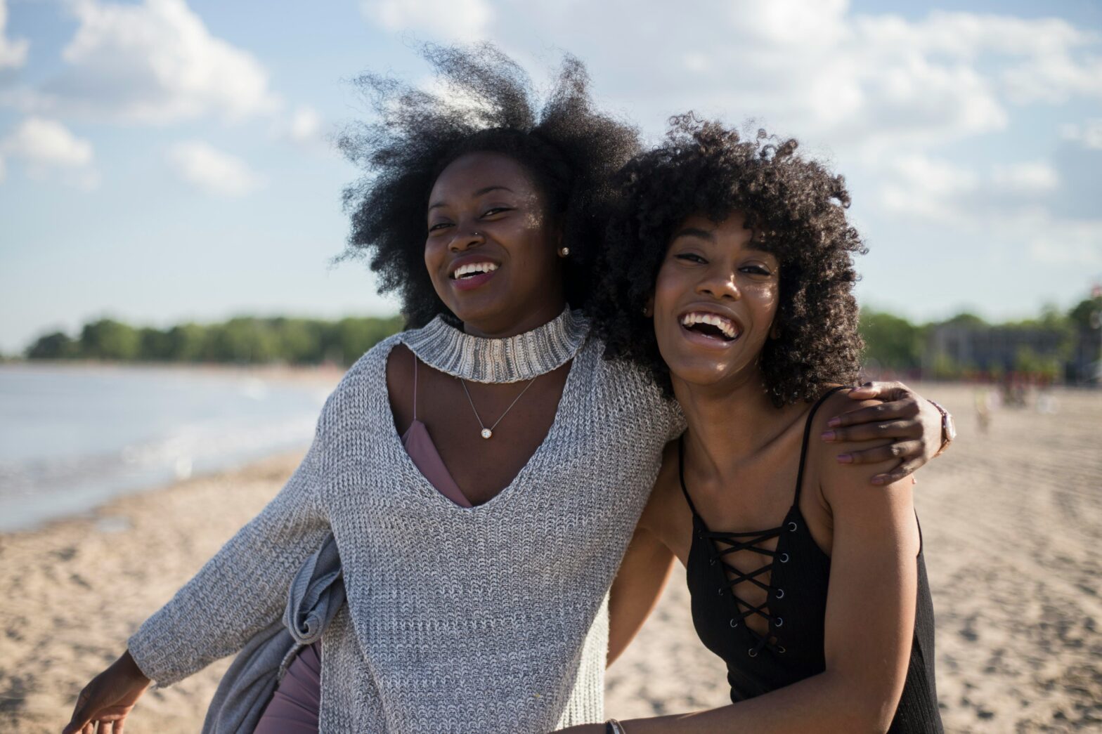 Black women smiling on a beach.