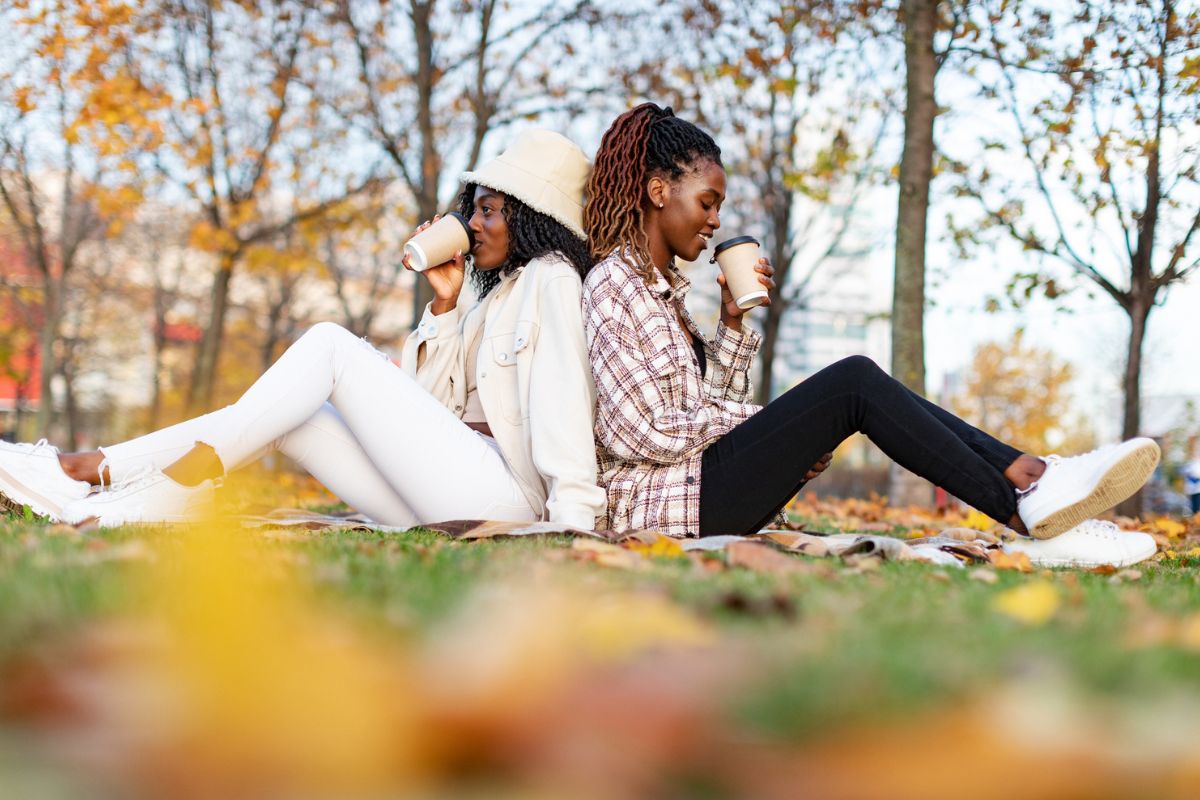 two friends sitting on the park in the fall