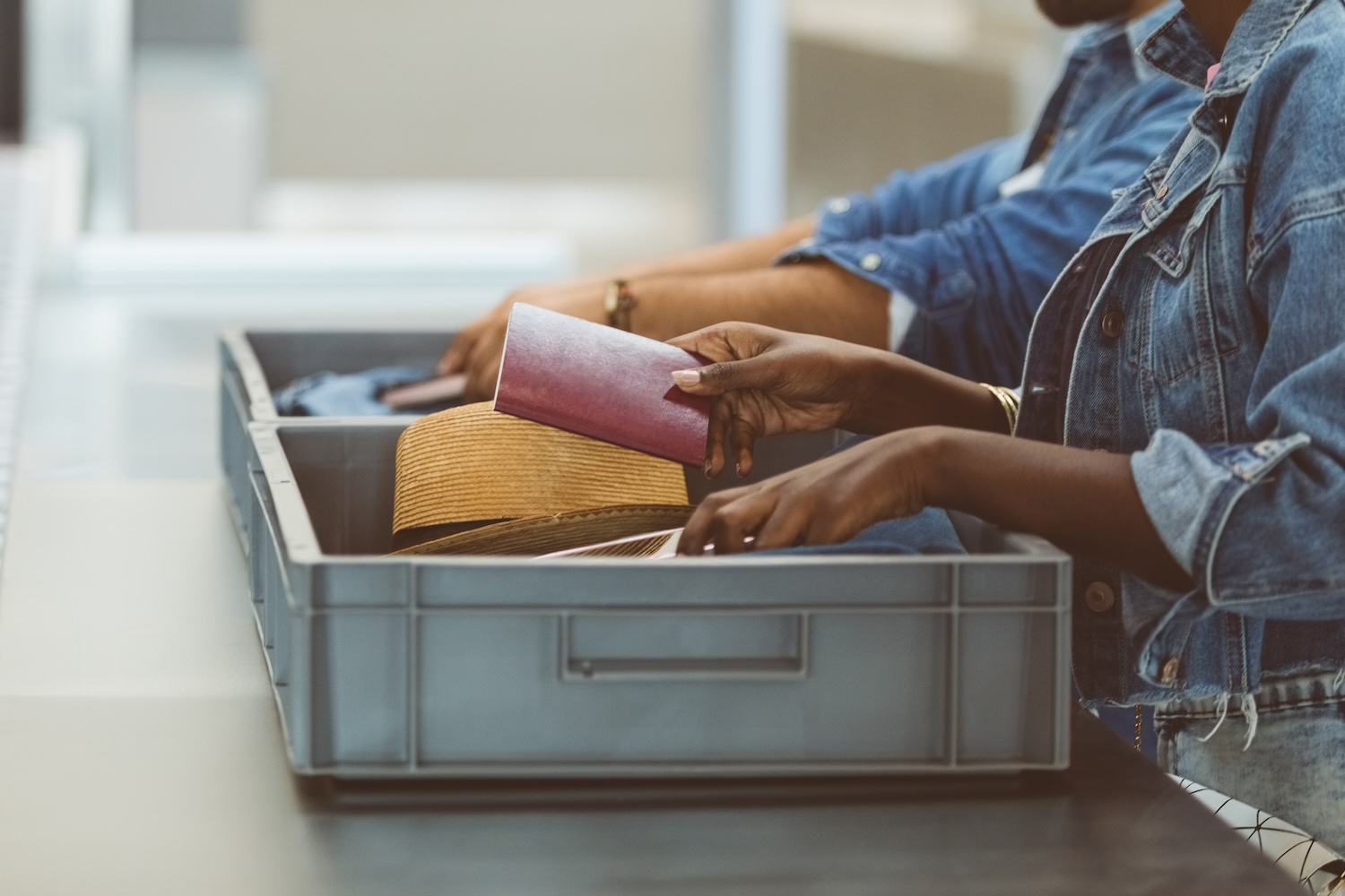 Midsection of woman picking passport from TSA tray at airport security check.