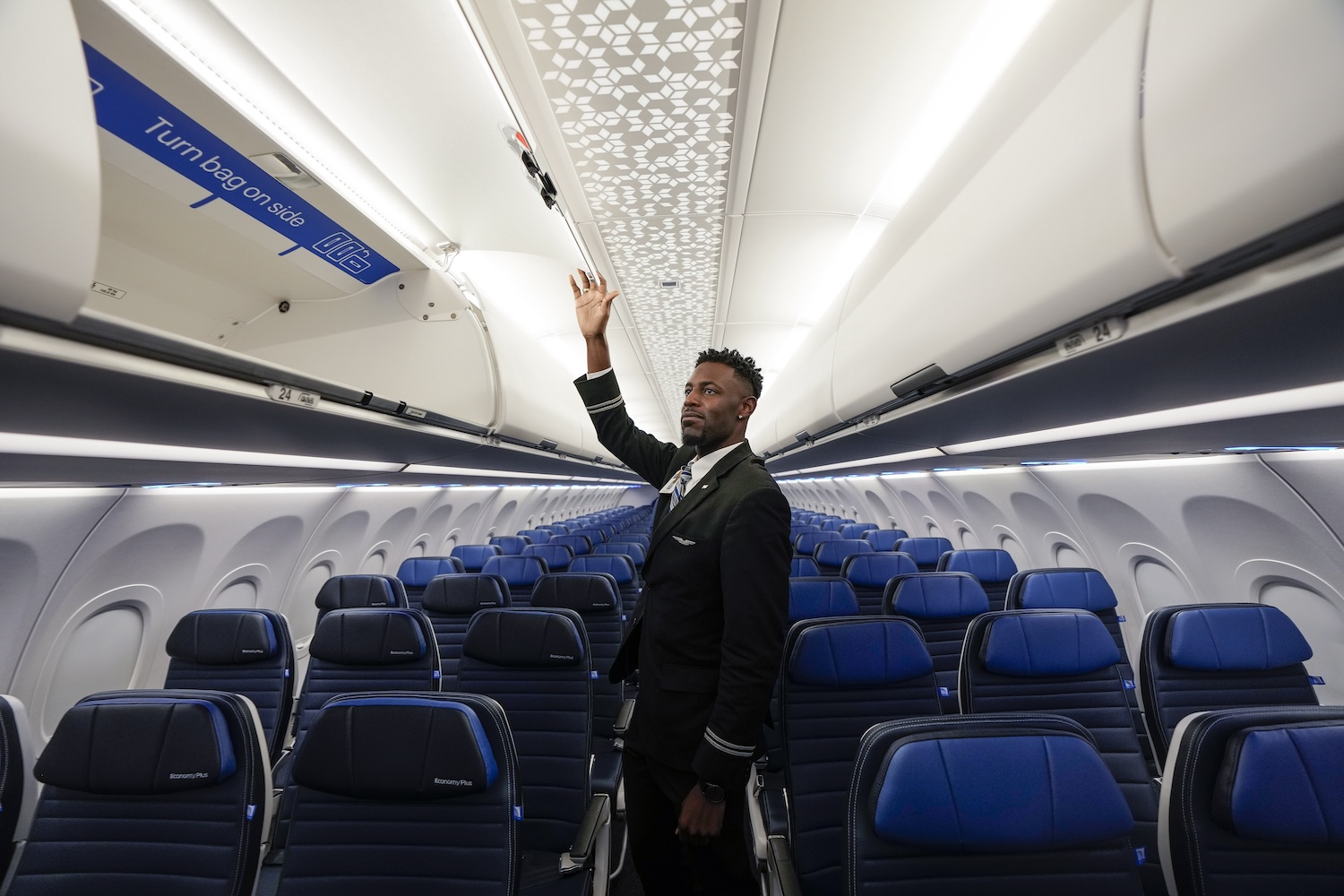 Flight attendant Nicholas Johnson opens the overhead luggage bin on United Airlines new Airbus A321neo.