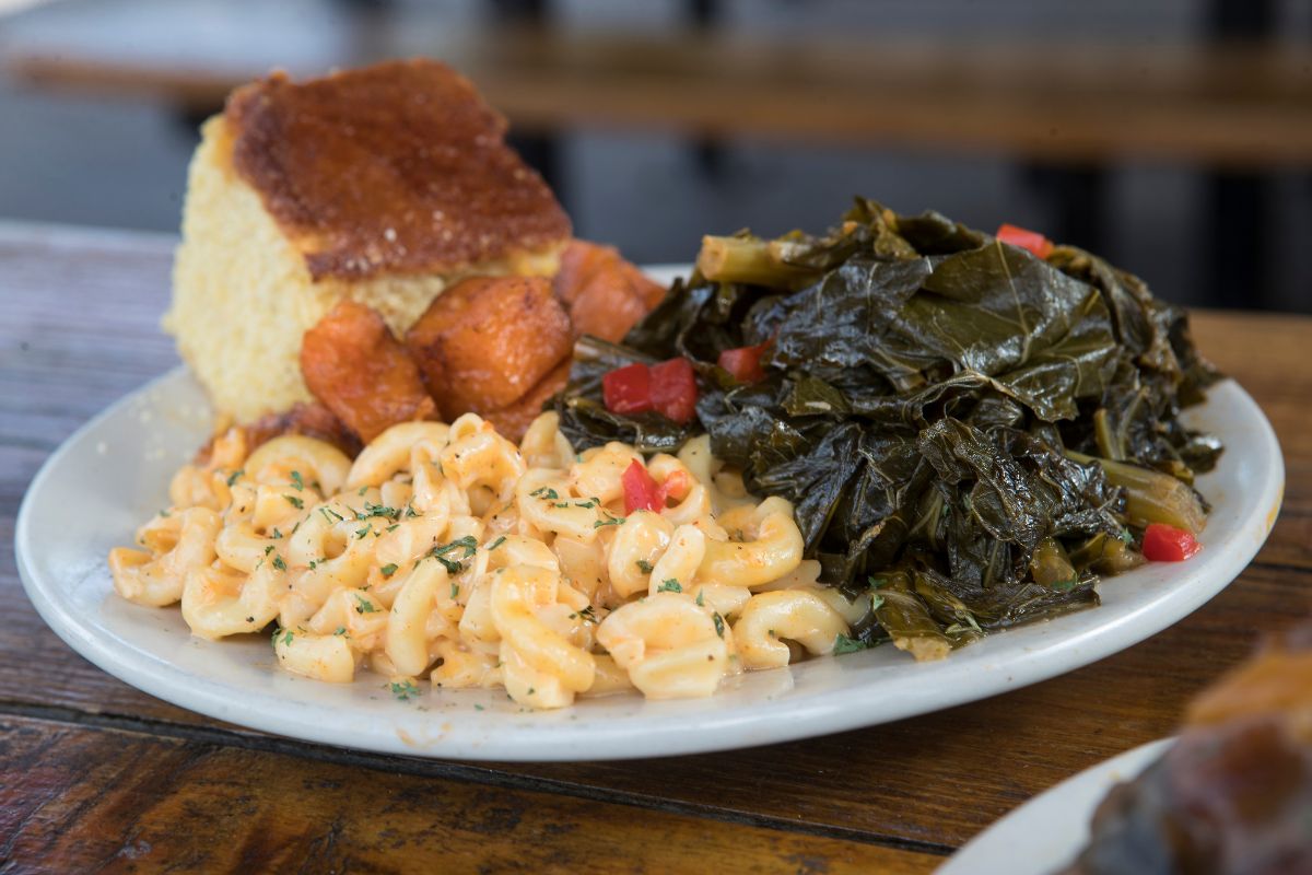 A plate of collard greens, macaroni and cheese, candied yams and cornbread