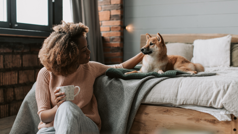 African American woman petting her dog on the bed