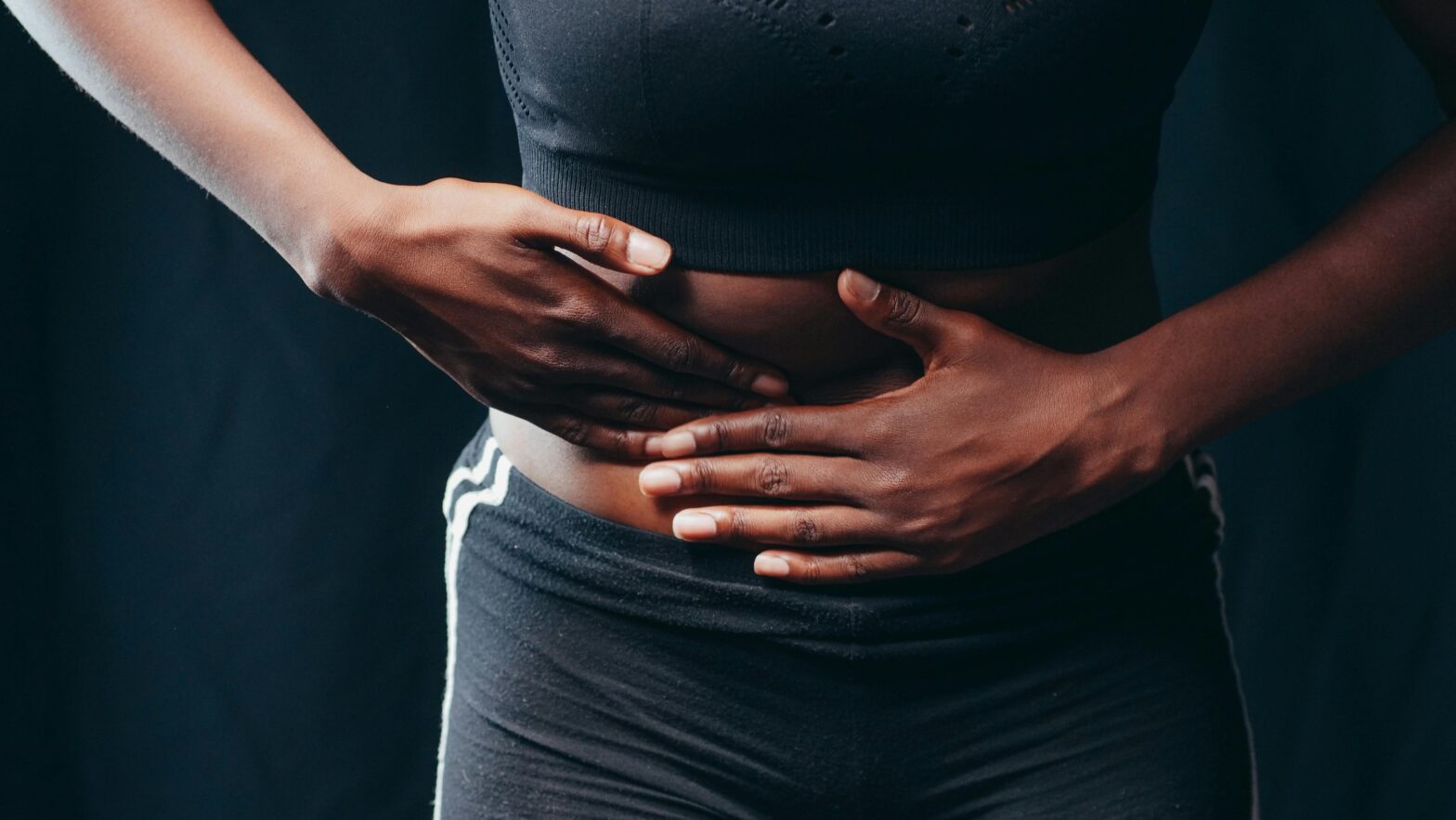 Travel constipation is an issue that many people silently endure. Here are some reasons and solutions. Pictured: Black woman holding stomach in pain