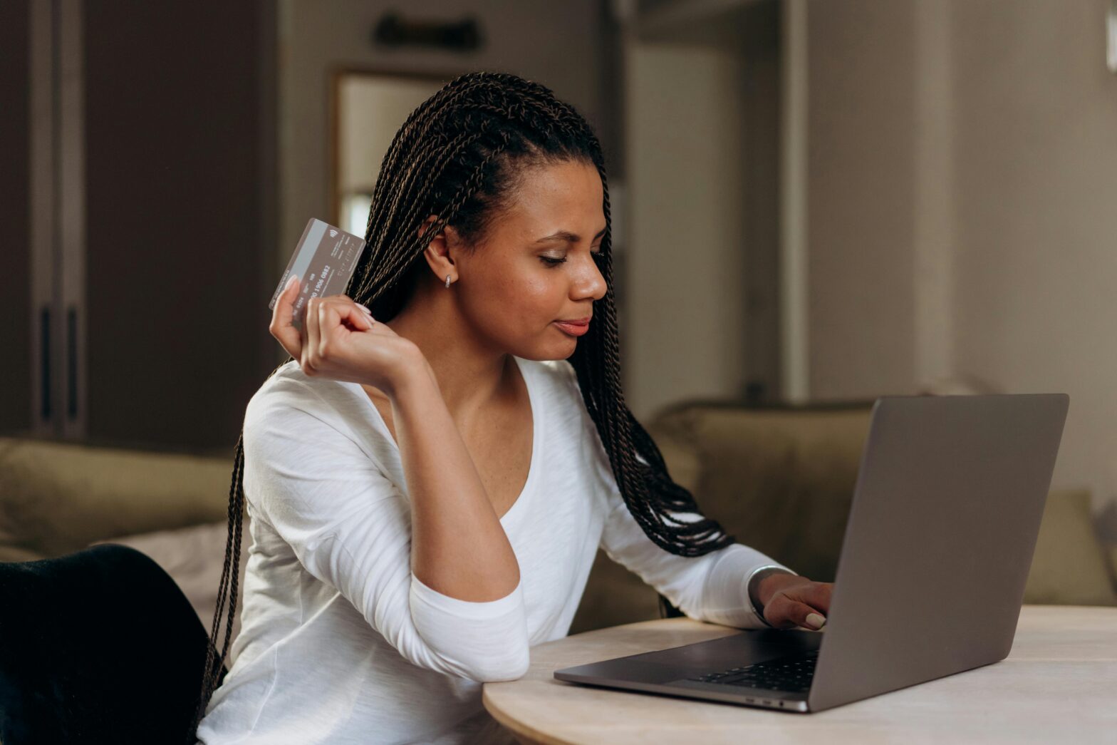 Woman Holding Credit Card While on Laptop