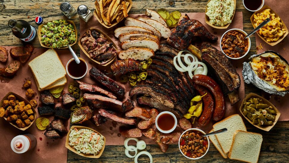 Table full of ribs, casserole, BBQ hot dogs and French fries