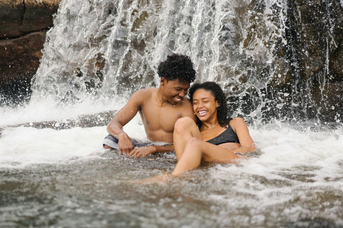 young man and woman splashing in a waterfall