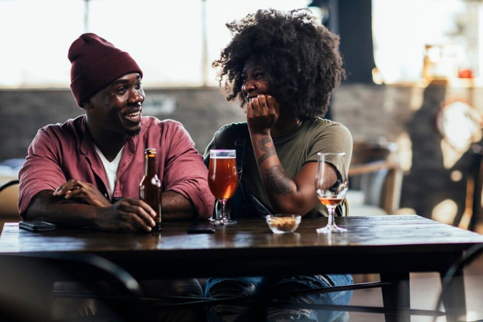 Black couple sitting at restaurant drinking beer together