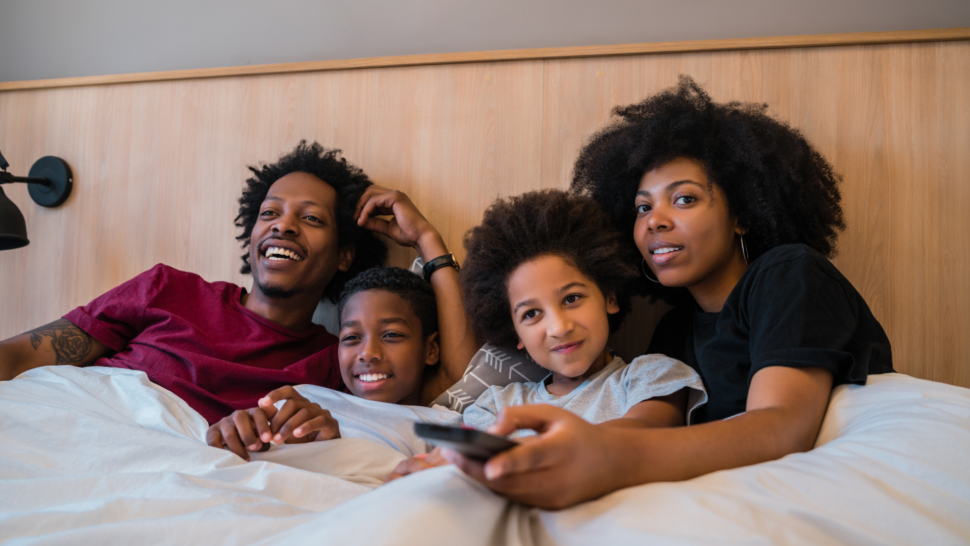 Family in hotel bedroom watching TV