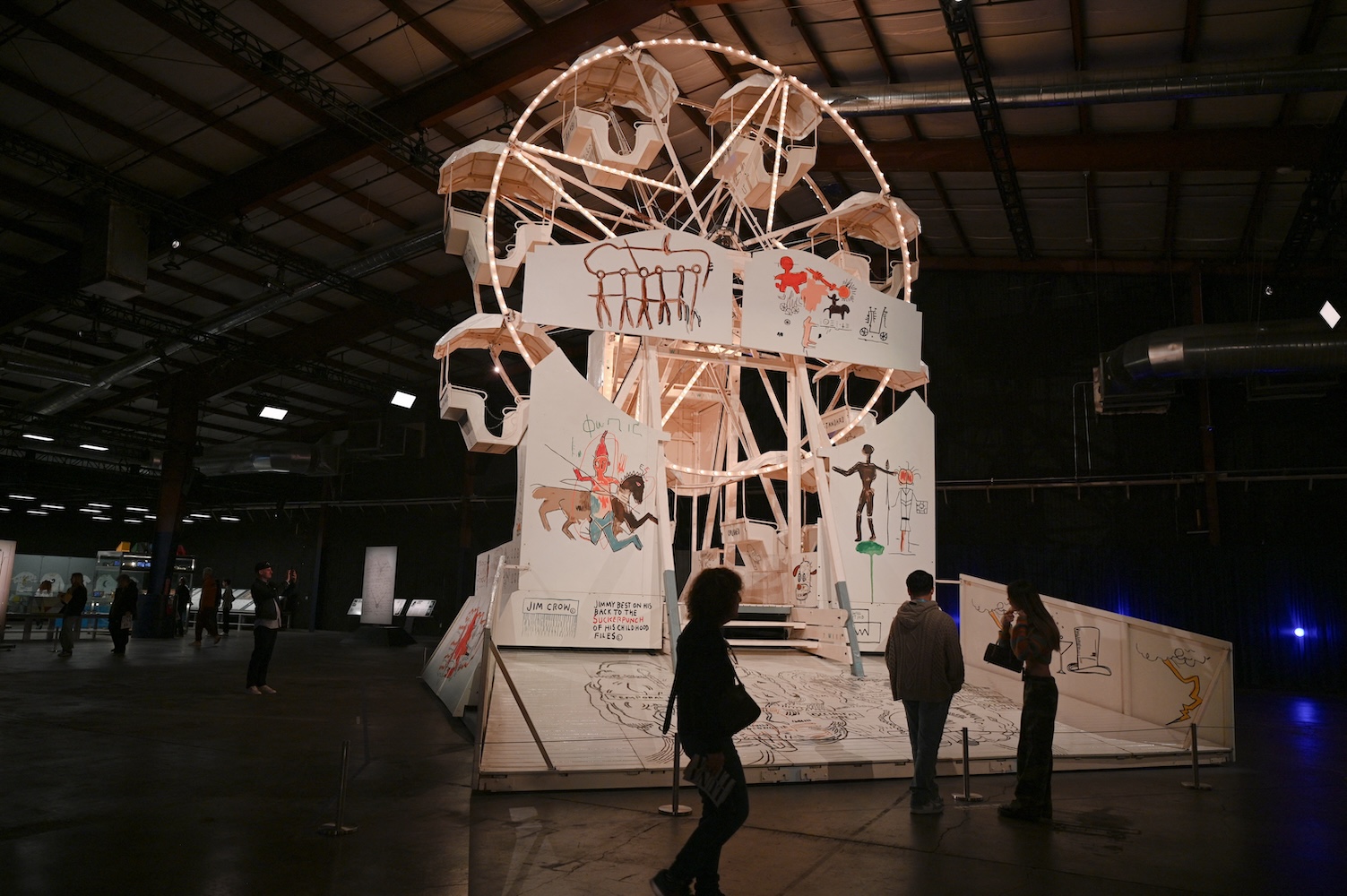 Visitors experience a Painted Ferris Wheel by Jean-Michel Basquiat at "Luna Luna: Forgotten Fantasy."