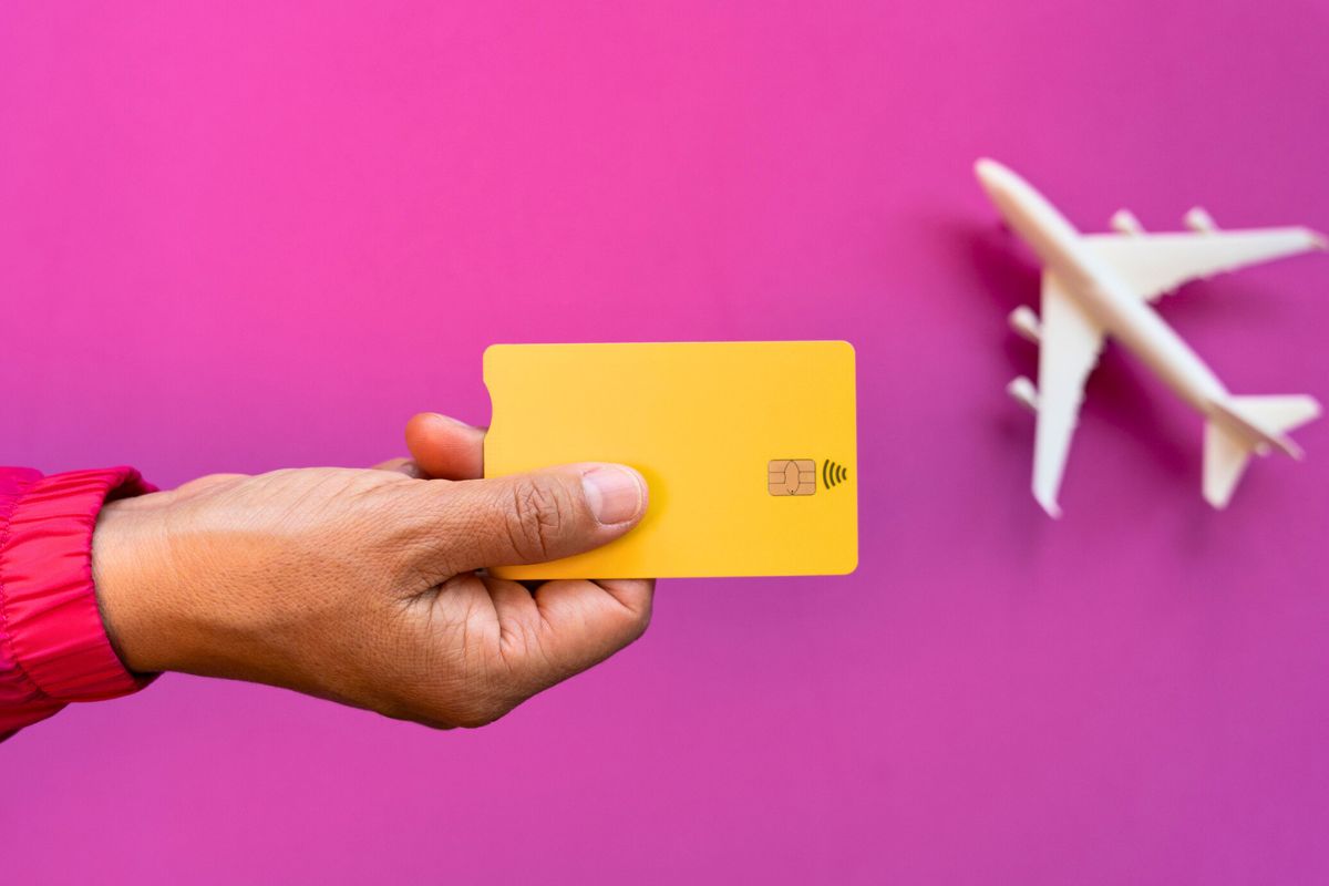 person holding a debit card with a miniature plane in the background