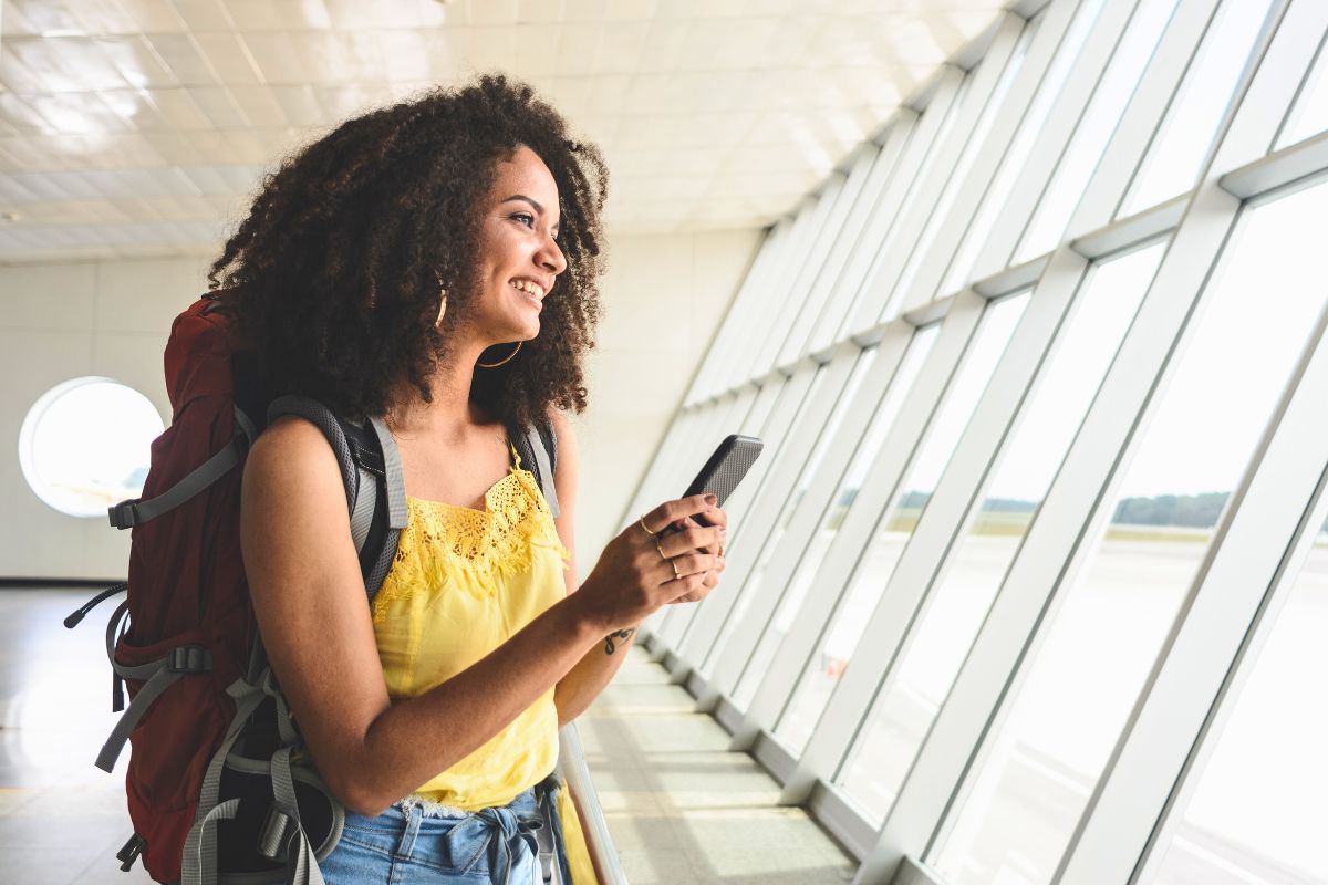 traveler with backpack on phone at airport