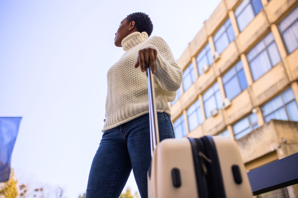 woman walking with suitcase looking up at sky