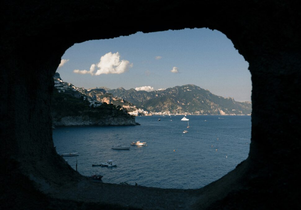 A view of the Amalfi Coast in Italy as seen through a natural rock structure. 