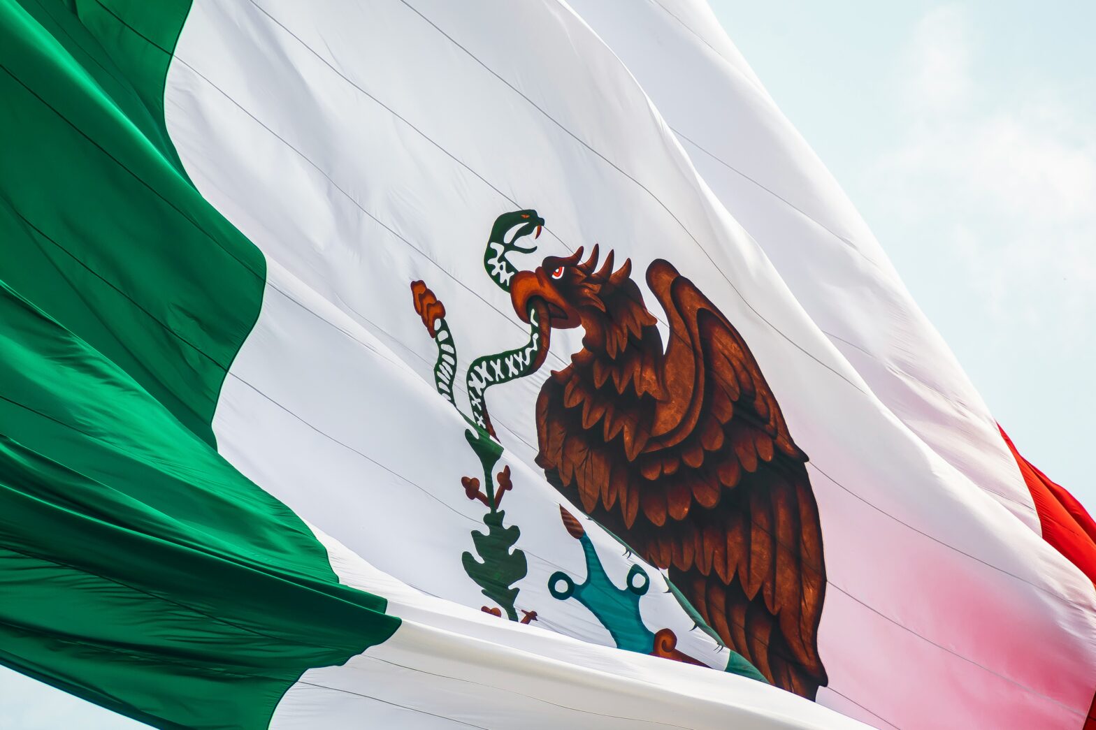 Mexican flag waving in the day sky.