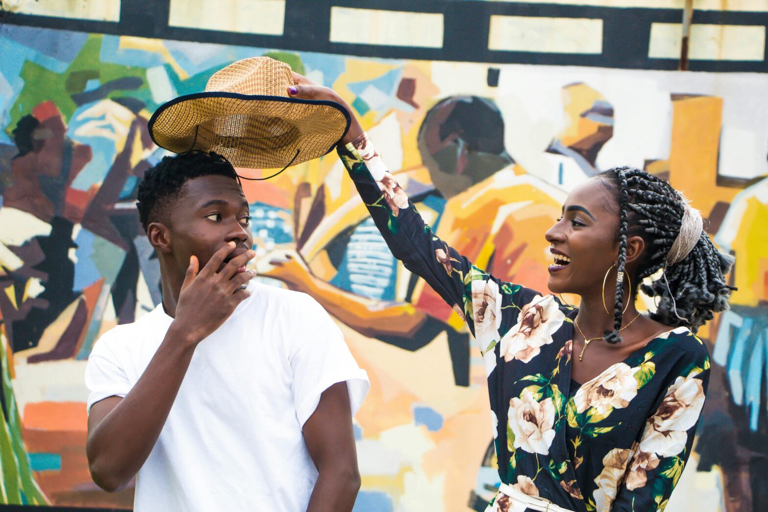 Smiling woman putting a hat on a surprised man.