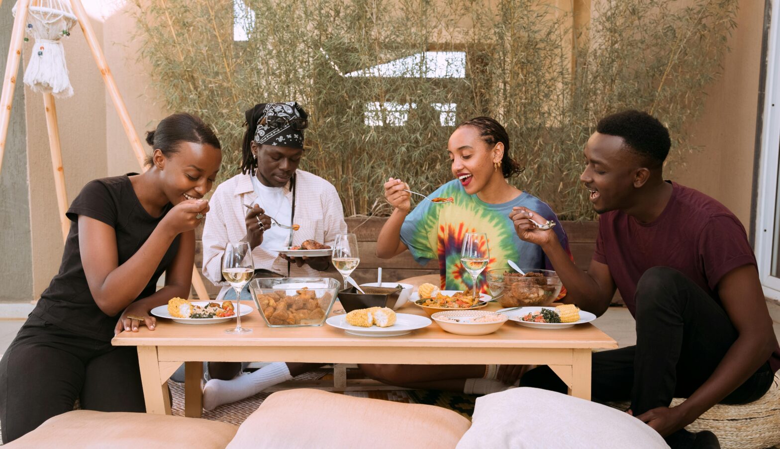 Four Black friends sitting at a table eating and talking.