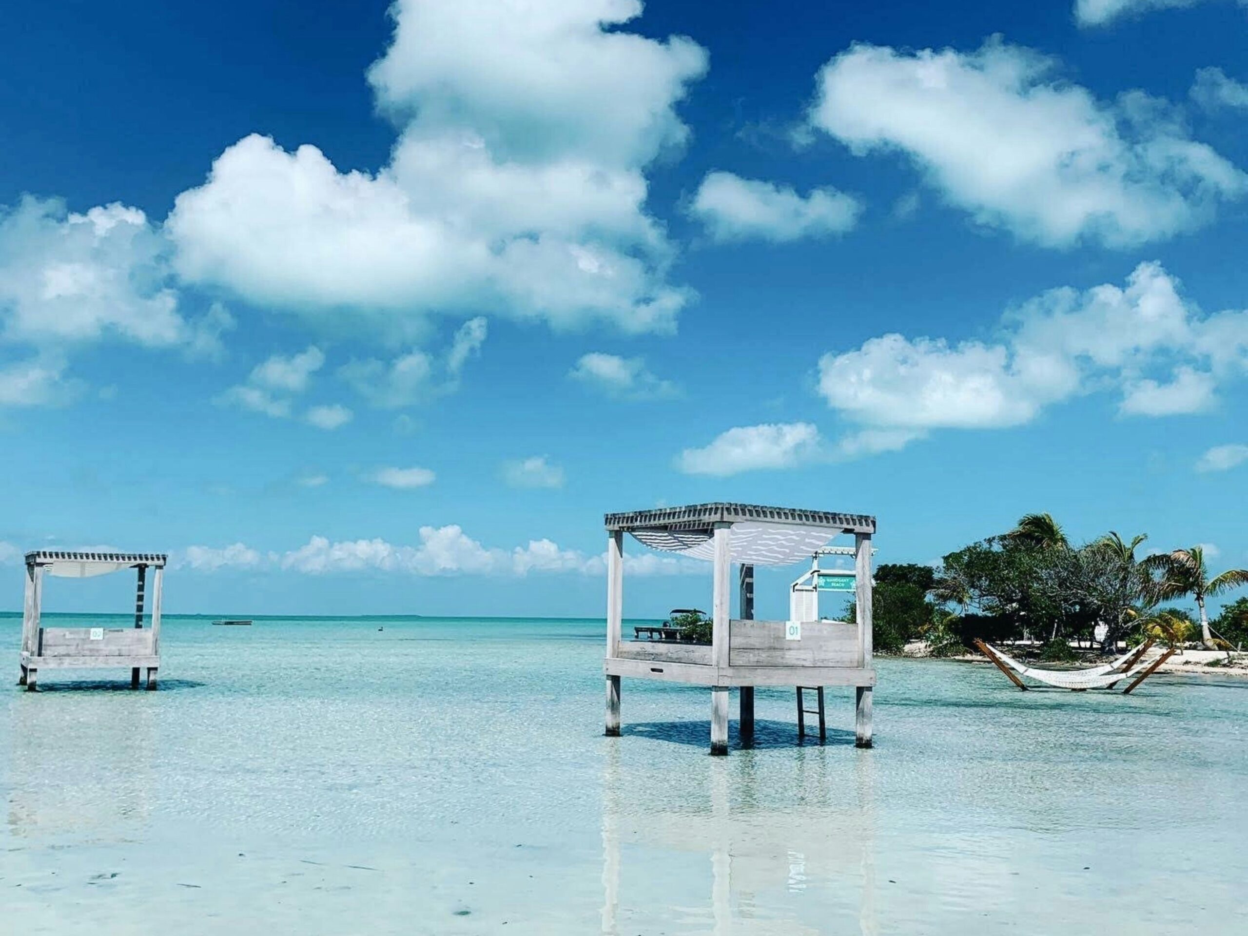 A beach in Belize with clear waters and lush vegetation.