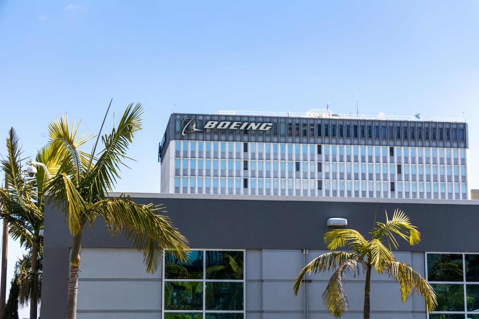 Exterior of Boeing office building during the day with palm tress in front.