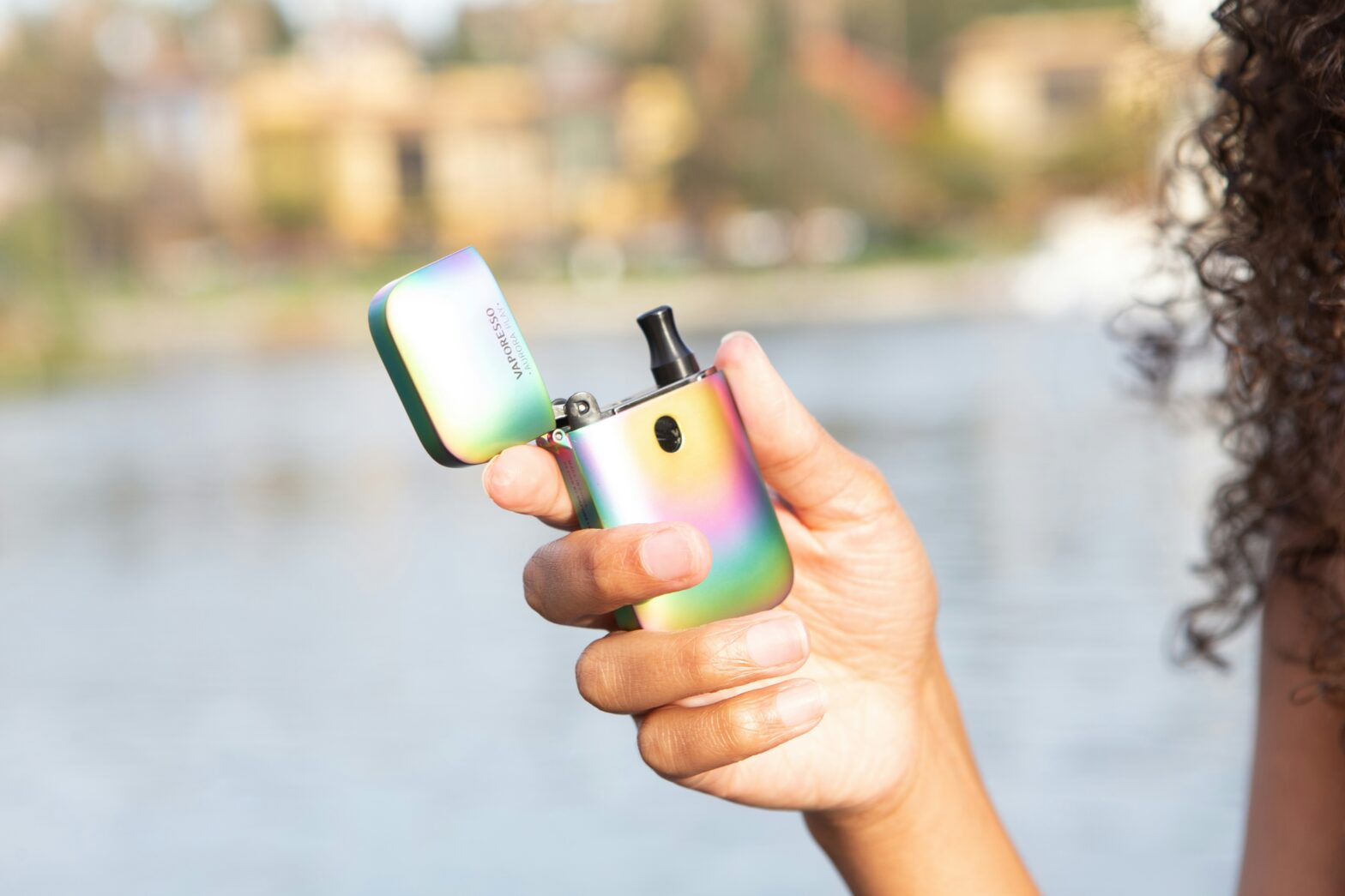 curly haired woman holding a vape