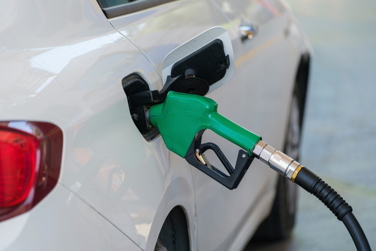 Gas pump nozzle in the fuel tank of a white car, refuel